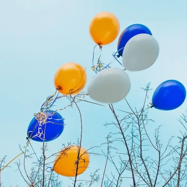 This is an image of helium ballons that are stuck on tress.